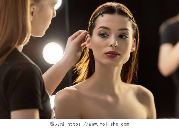 化妆师触摸年轻模特的头发化妆艺术家的选择焦点触摸年轻模特的头发 